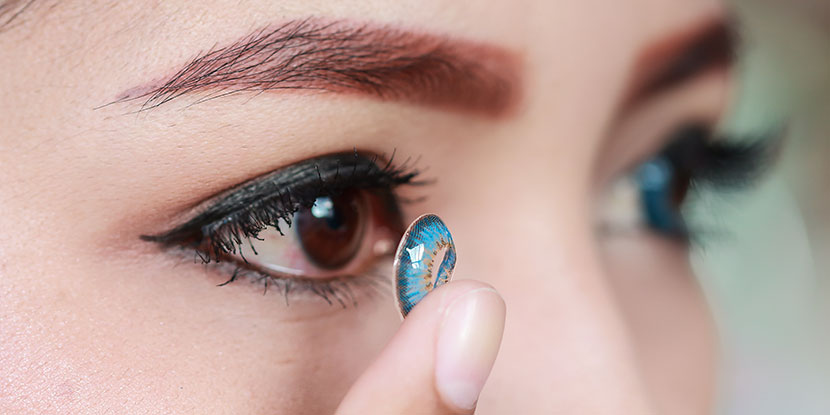 a woman insterting lens into her eye
