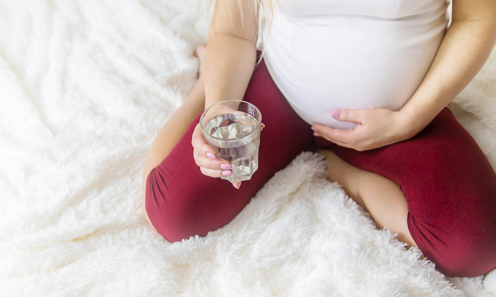 pregnant woman holding a glass full of water