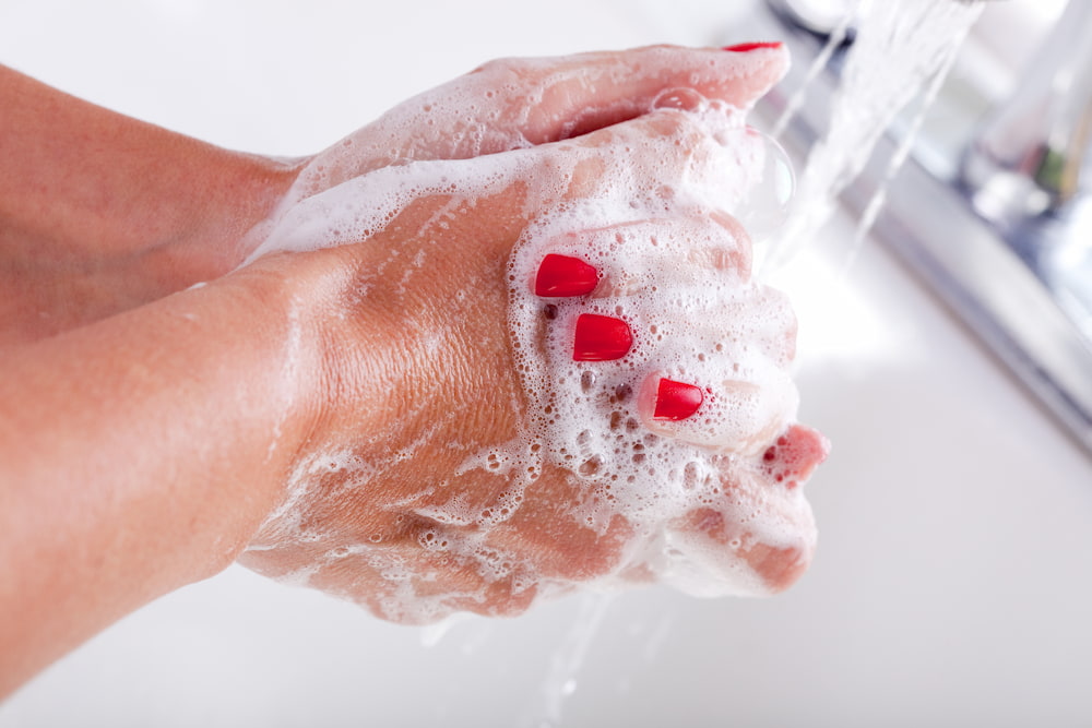 hands with red nail polish washing